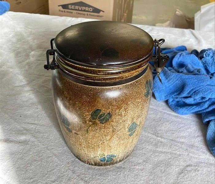 Ceramic jar heavily covered with smoke following a fire.