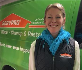 Female SERVPRO employee in front of green van wearing black vest.