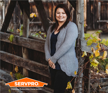 Female SERVPRO employee on a wood bridge with orange SERVPRO logo in lower left corner.