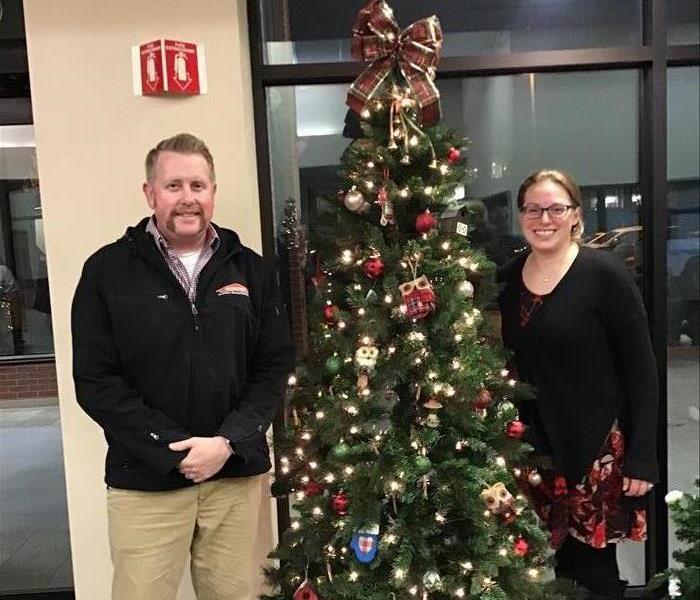 a man and a woman standing next to a Christmas tree