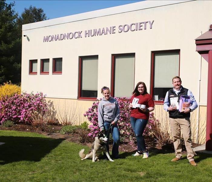 A photo of three people standing outside of the humane society