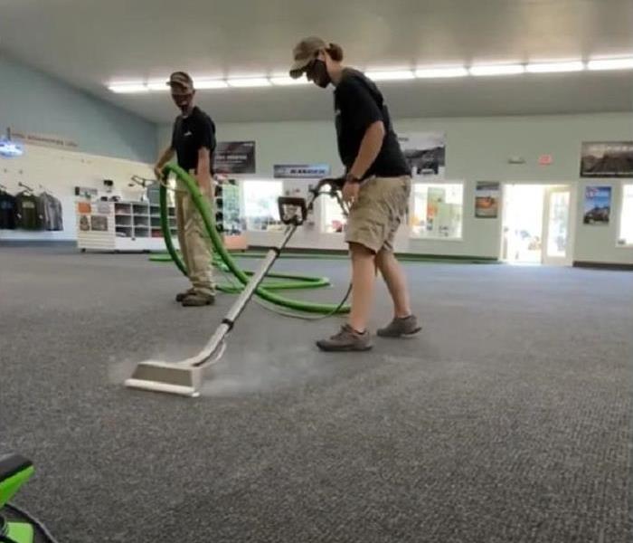 Technicians cleaning carpeting in a retail space.