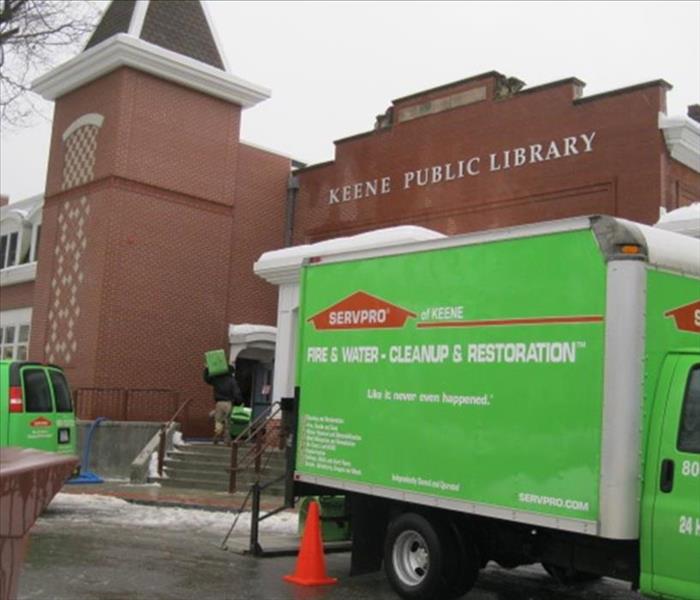 Green trucks parked outside public library.