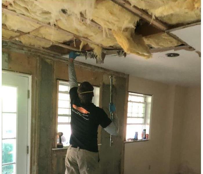 A SERVPRO technician tearing down a ceiling as a result of water damage